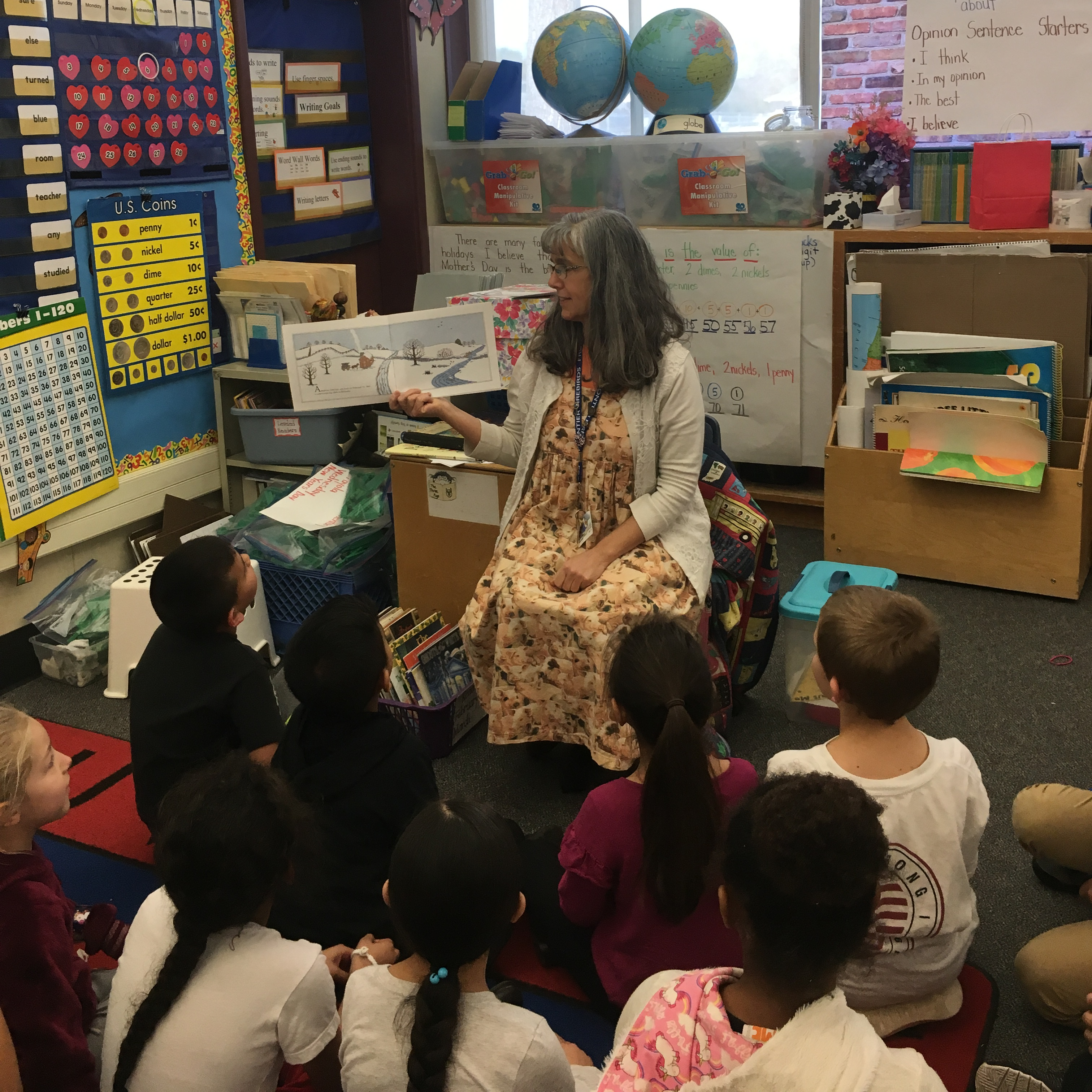 teacher reading book to students seated on carpet